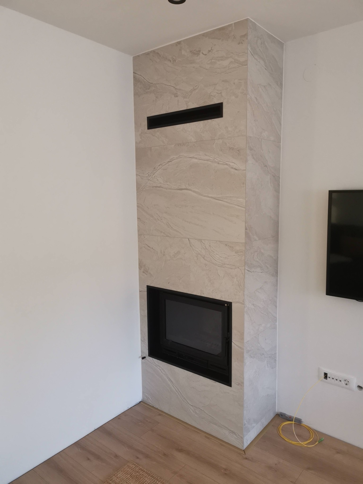 Minimalistički ugradbeni kamin sa svijetlom oblogom u modernom interijeru